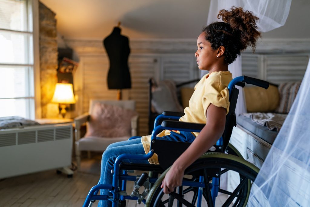 Black little girl with disability in wheelchair at home